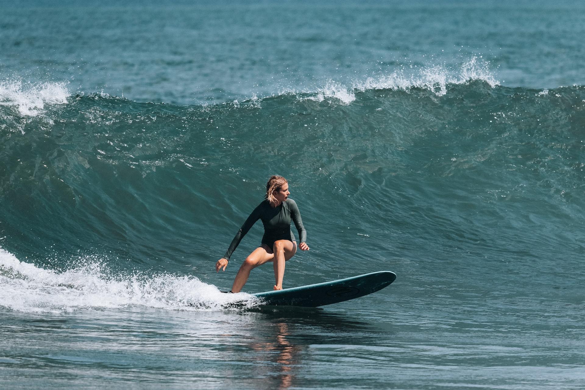 A surfer finding her flow on a turquoise wave in Bali